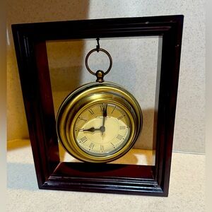 Elegant Brushed antique Gold round clock suspended in middle of wood frame.